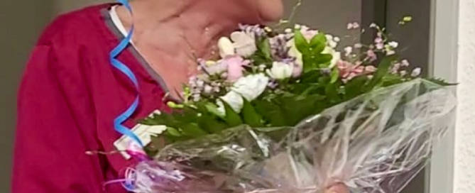 Mitarbeiterin Diana hält einen Blumenstrauß in den Händen und lacht freudig.