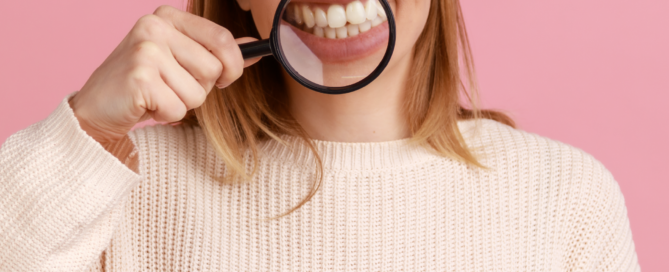 Eine Frau lächelt und hält eine Lupe vor ihren Mund.